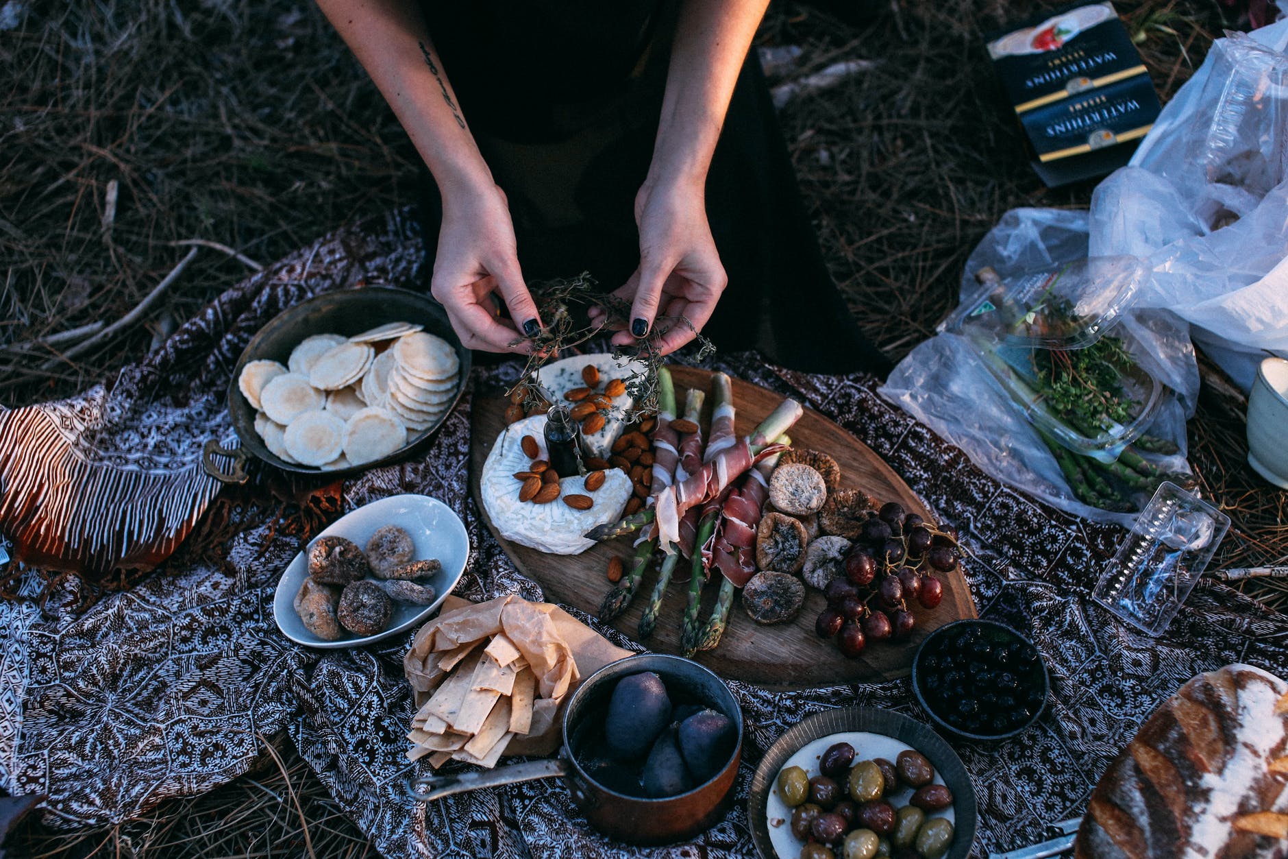crop unrecognizable woman serving delicious snacks on plaid for picnic